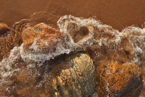 Directamente por encima de la toma de pequeñas olas rodando en la playa formando una forma de corazón en el agua espumosa —  Fotos de Stock