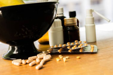 Geniş bir hap grubu, su toplayan paketler ve ilaç şişesi. Havan topu ve tokmak