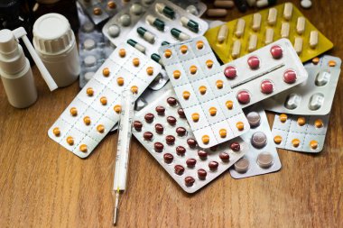 Geniş bir hap grubu, su toplayan paketler ve ilaç şişesi. Havan topu ve tokmak