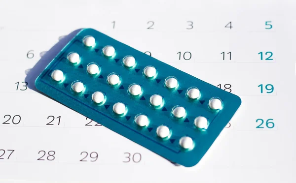 Contraceptive Pills on calendar background. Pregnancy care concept.