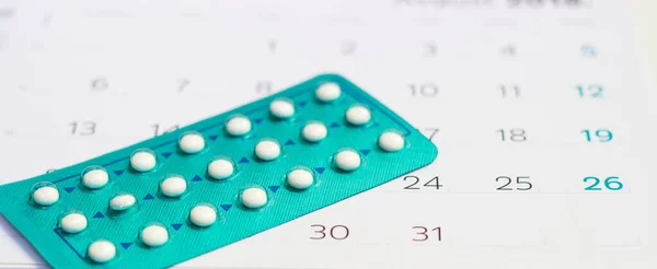 Contraceptive Pills on calendar background. Pregnancy care concept.