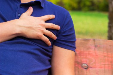 Göğüs ağrısı çeken, acı çeken bir adam. Dışarıda oturuyor.