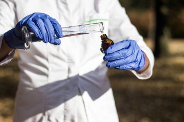 Test tüplü, açık havada, arka planda kadın kimyager.