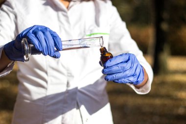 Test tüplü, açık havada, arka planda kadın kimyager.