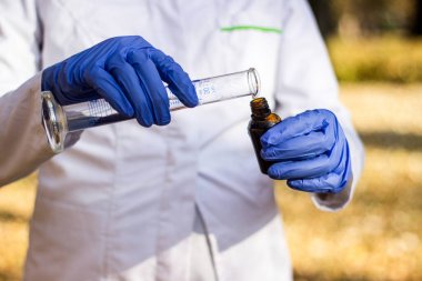 Test tüplü, açık havada, arka planda kadın kimyager.