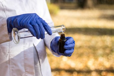 Test tüplü, açık havada, arka planda kadın kimyager.