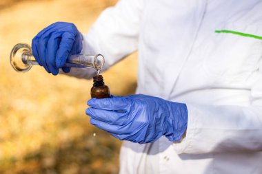 Test tüplü, açık havada, arka planda kadın kimyager.