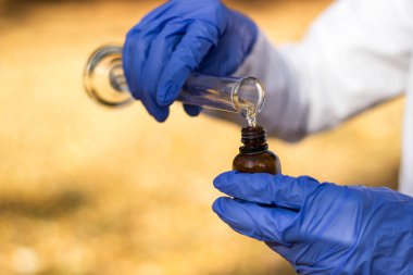 Test tüplü, açık havada, arka planda kadın kimyager.