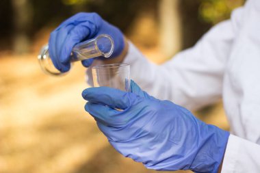 Test tüplü, açık havada, arka planda kadın kimyager.