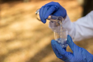 Test tüplü, açık havada, arka planda kadın kimyager.