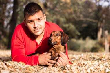 Genç bir adam köpeğiyle eğleniyor.