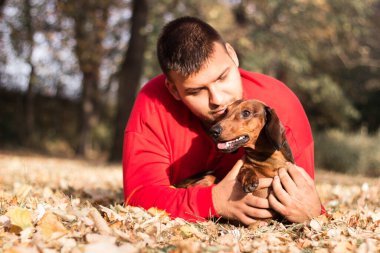Genç bir adam köpeğiyle eğleniyor.