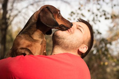 Genç bir adam köpeğiyle eğleniyor.
