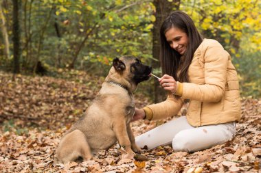 Mutlu, gülümseyen bir kadın. Köpeğini kucaklıyor, parkta uzanıyor.