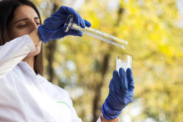 Test tüplü, açık havada, arka planda kadın kimyager.