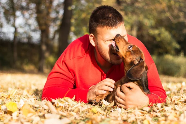 Genç bir adam köpeğiyle eğleniyor.