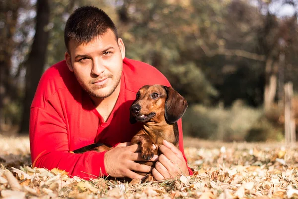 Genç bir adam köpeğiyle eğleniyor.