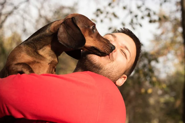 Genç bir adam köpeğiyle eğleniyor.
