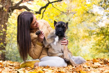 Mutlu, gülümseyen bir kadın. Köpeğini kucaklıyor, parkta uzanıyor.