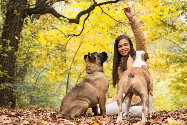 Mutlu, gülümseyen bir kadın. Köpeğini kucaklıyor, parkta uzanıyor.