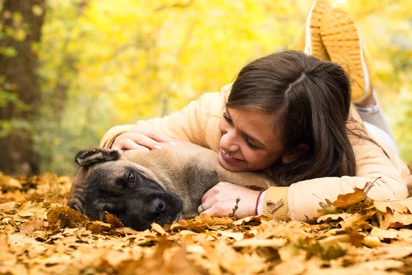 Mutlu, gülümseyen bir kadın. Köpeğini kucaklıyor, parkta uzanıyor.