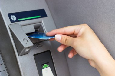 Kadının eli kredi kartını ATM 'ye koyup kapatıyor.