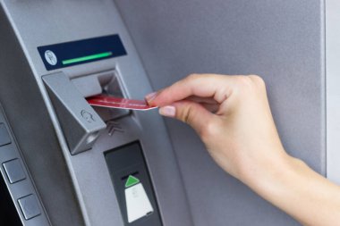 Kadının eli kredi kartını ATM 'ye koyup kapatıyor.