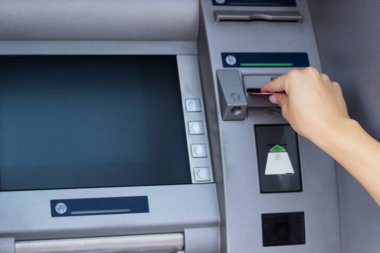Kadının eli kredi kartını ATM 'ye koyup kapatıyor.