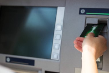 Kadının eli kredi kartını ATM 'ye koyup kapatıyor.