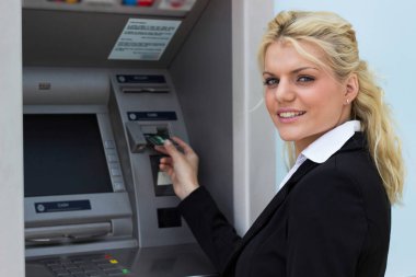 Gülümseyen iş kadını ATM 'de kredi kartından para çekiyor.