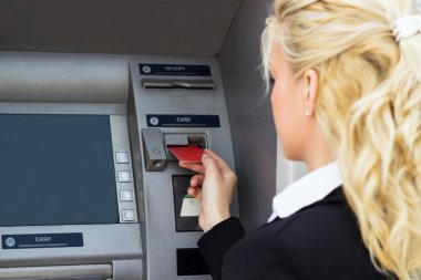 Gülümseyen iş kadını ATM 'de kredi kartından para çekiyor.
