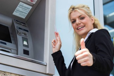 Gülümseyen iş kadını ATM 'de kredi kartından para çekiyor.
