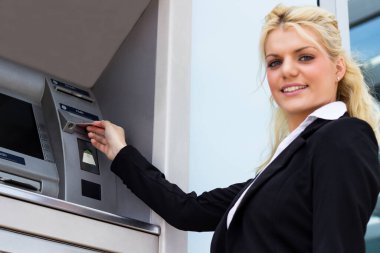 Gülümseyen iş kadını ATM 'de kredi kartından para çekiyor.