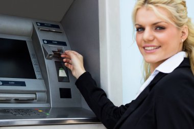 Gülümseyen iş kadını ATM 'de kredi kartından para çekiyor.