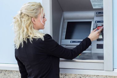 Gülümseyen iş kadını ATM 'de kredi kartından para çekiyor.