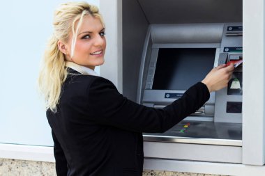 Gülümseyen iş kadını ATM 'de kredi kartından para çekiyor.