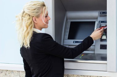 Gülümseyen iş kadını ATM 'de kredi kartından para çekiyor.