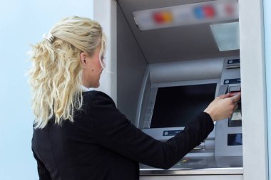 Gülümseyen iş kadını ATM 'de kredi kartından para çekiyor.