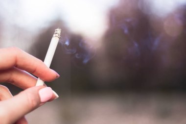 Sigara içen genç bir kadın. Elde sigara.