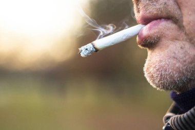 Son sınıf öğrencisi dışarıda sigara içiyor.