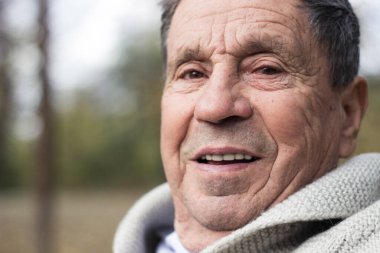 Açık havada, halka açık bir parkta gülümseyen son sınıf öğrencisinin portresi. Yaşlı adam dışarıda dinleniyor ve kameraya bakıyor. Emekliliğin tadını çıkaran yaşlı bir adamın portresi