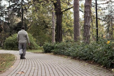 Yaşlı adam parkta yürüyor ve dinleniyor. Uzaklaşıyor, rahatlıyor, dikiz aynasından bakıyor.