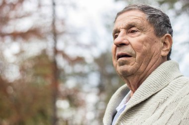 Yaşlı adam dışarıda dinleniyor ve aşağıya bakıyor. Son sınıf öğrencisinin portresi düşünceli görünüyor.