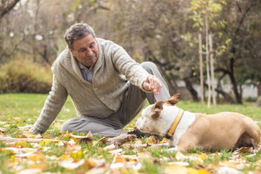Köpeğiyle çimenlerde oynayan gülümseyen son sınıf öğrencisinin portresi.