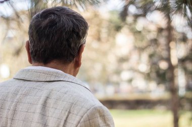 Kıdemli adam yürüyor, elleri bağlı. Kıdemli adam parkta yürüyor ve dinleniyor.