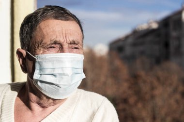 Koruyucu yüz maskesi takan yaşlı bir adamın portresi. Sağlık güvenliği kavramı