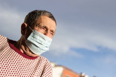 Koruyucu yüz maskesi takan yaşlı bir adamın portresi. Sağlık güvenliği kavramı