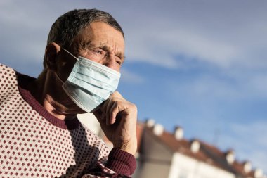 Koruyucu yüz maskesi takan yaşlı bir adamın portresi. Sağlık güvenliği kavramı