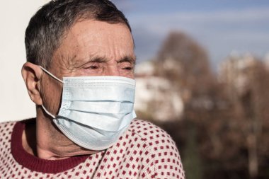 Koruyucu yüz maskesi takan yaşlı bir adamın portresi. Sağlık güvenliği kavramı