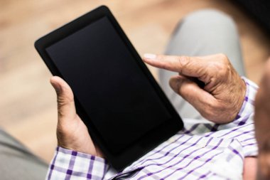 Evde modern dijital tablet kullanan kıdemli bir adam.